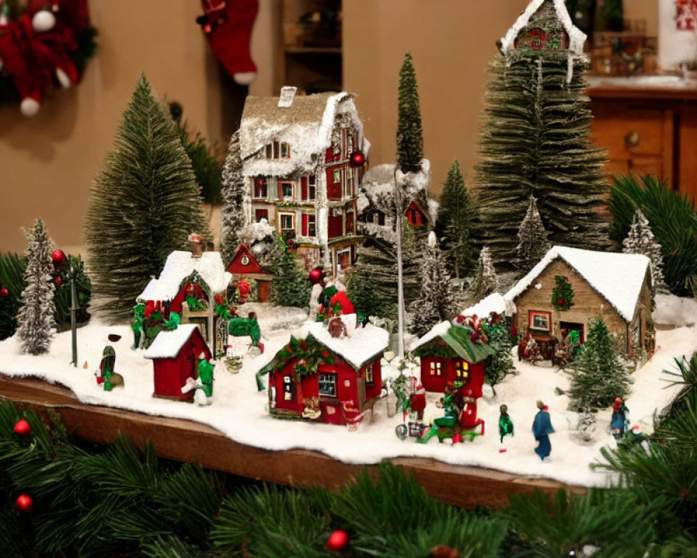 Snow-covered miniature festive village with pine trees and Christmas decorations