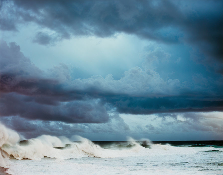 Turbulent seascape with towering clouds and waves in blue and gray