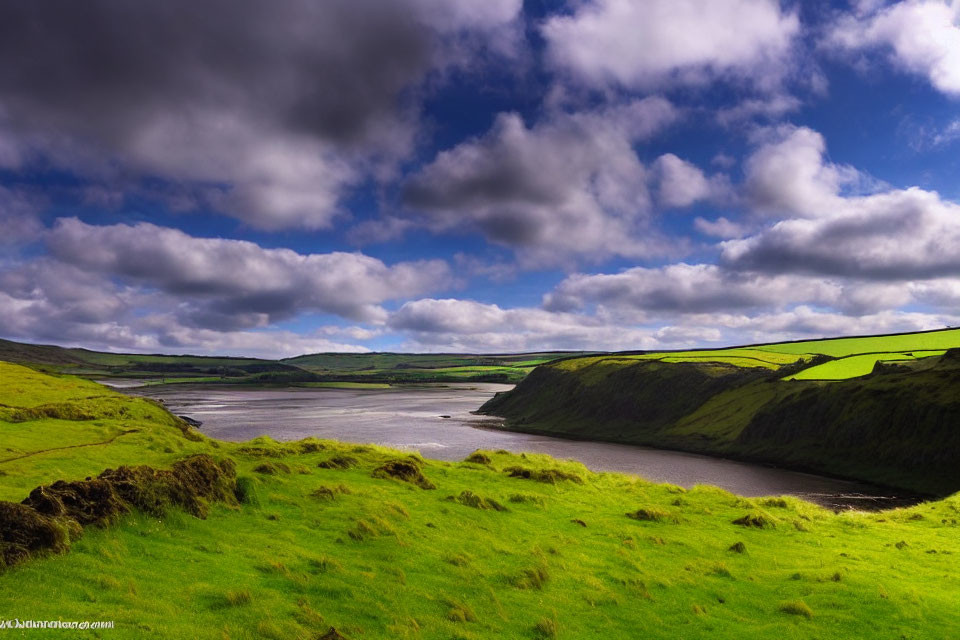 Scenic landscape: green hills, cliffs, river estuary, dynamic sky.