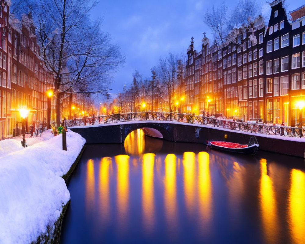 Snow-lined canal in Amsterdam with illuminated townhouses and bridge at winter dusk