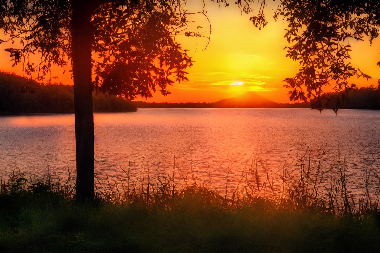 Tranquil sunset over calm lake with silhouetted trees and hills