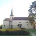 Historic church with people outside, clear sky, birds, and trees.