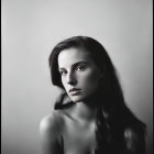 Monochrome portrait of a woman with long hair gazing thoughtfully.