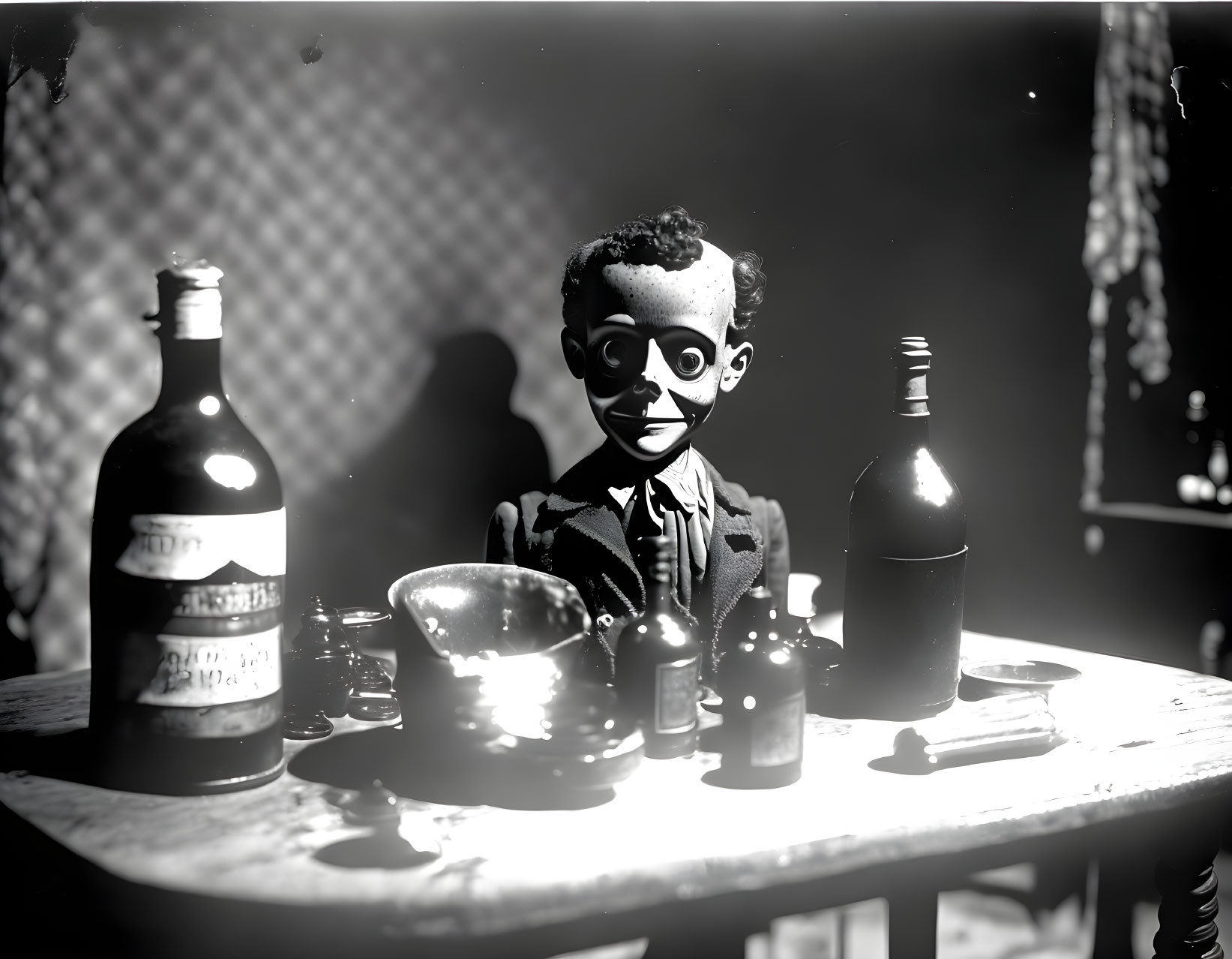 Monochrome image of ventriloquist's dummy at table with bowl and bottles