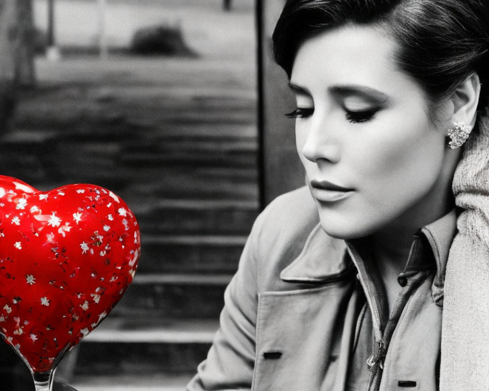 Monochrome photo of woman with red heart balloon outdoors