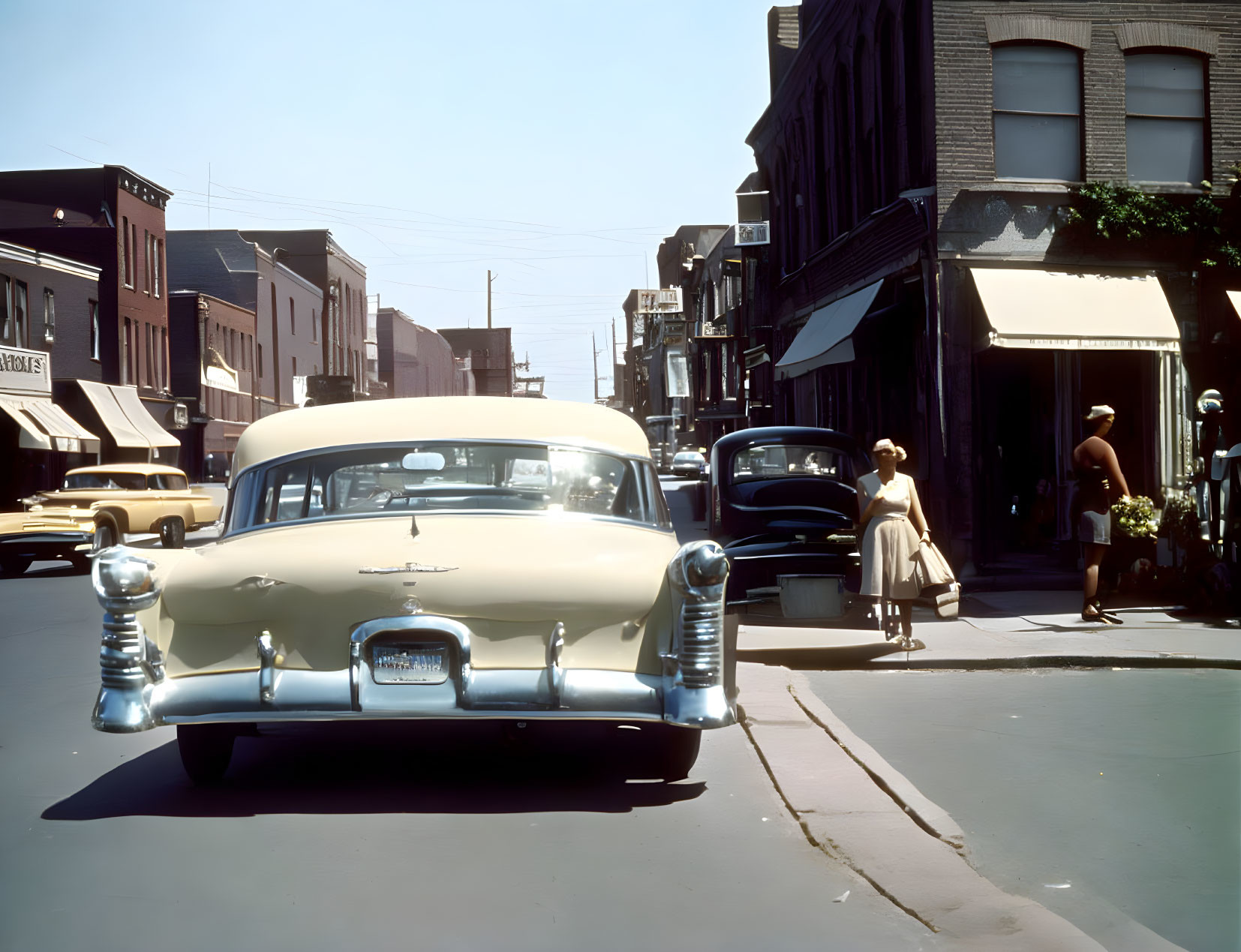 Classic cars, pedestrians, and old buildings in vintage street scene