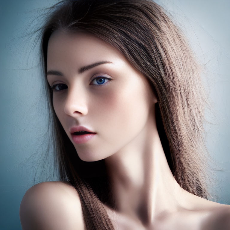 Young woman with blue eyes, smooth skin, and brown hair against blurred blue background