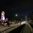 City street at night with colorful tower and lightning strikes