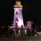 Snowy Night Scene: Festive Lighthouse Decorated with Santa Figures and Lanterns