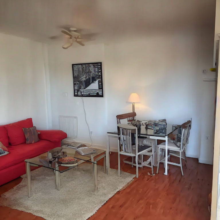 Red sofa, glass coffee table, white dining set, rug, wall art in a cozy living room