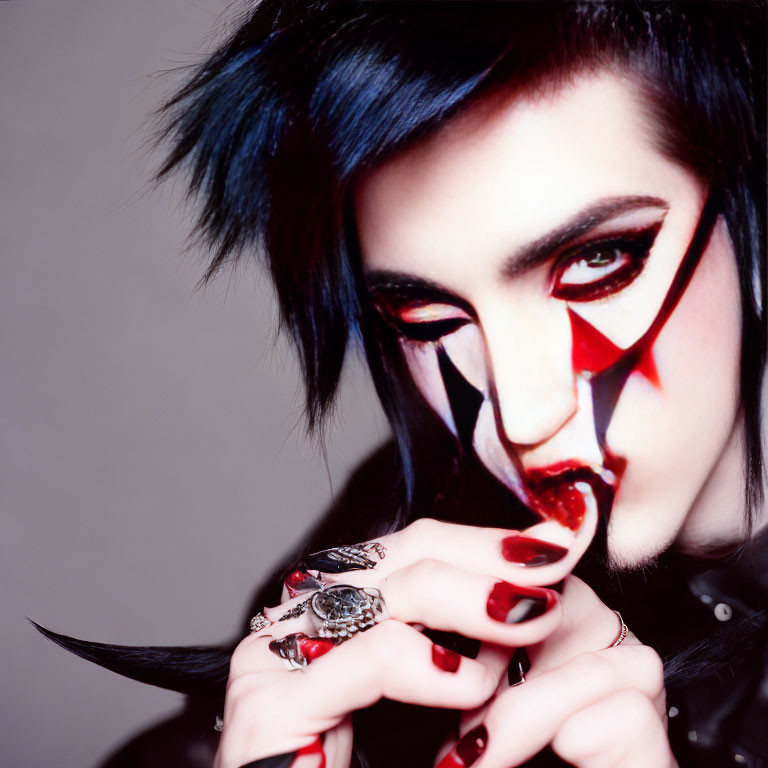 Dramatic makeup with red and black design, gothic style, blue-streaked black hair