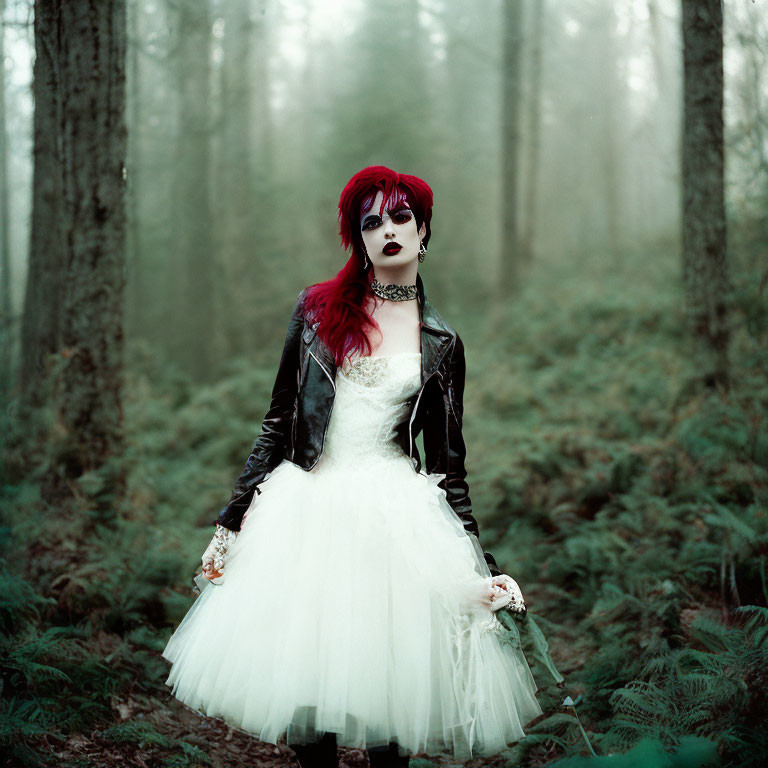 Red-haired woman in gothic makeup in white dress and leather jacket in misty forest