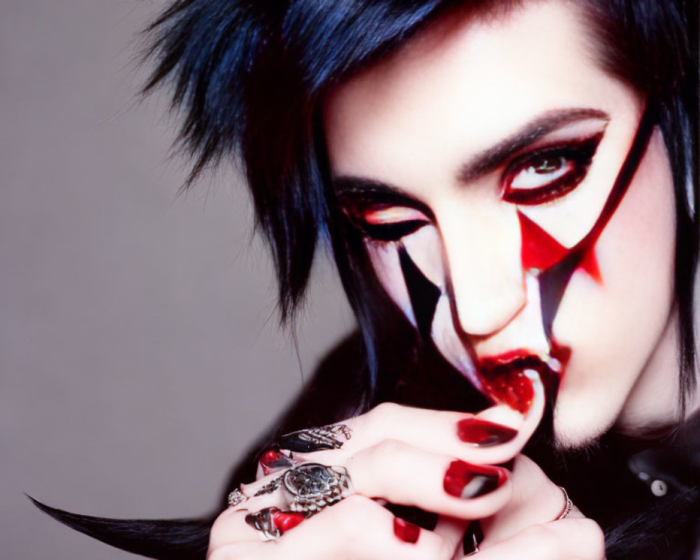 Dramatic makeup with red and black design, gothic style, blue-streaked black hair