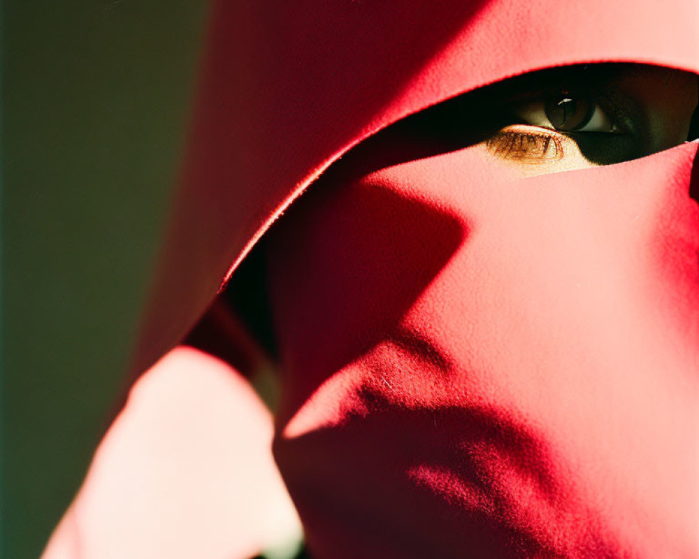 Eye peeking from red fabric under sunlight shadows