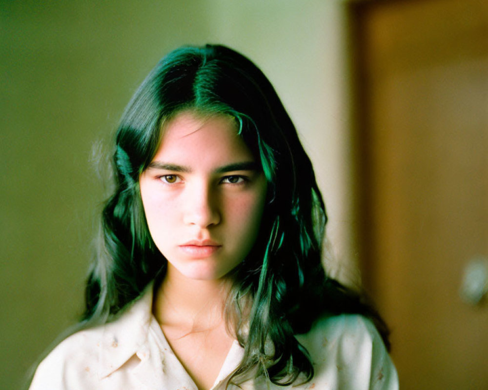 Dark-haired young woman in natural light against blurred indoor background