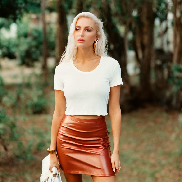 Blonde Woman in White Top and Brown Leather Skirt Standing in Wooded Area