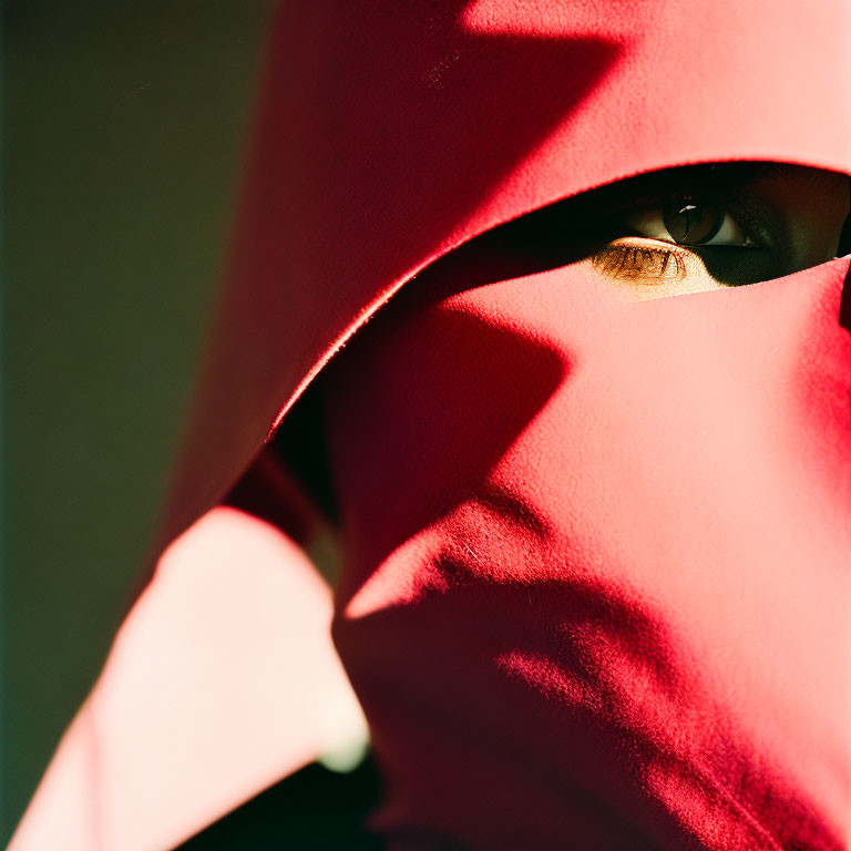 Eye peeking from red fabric under sunlight shadows