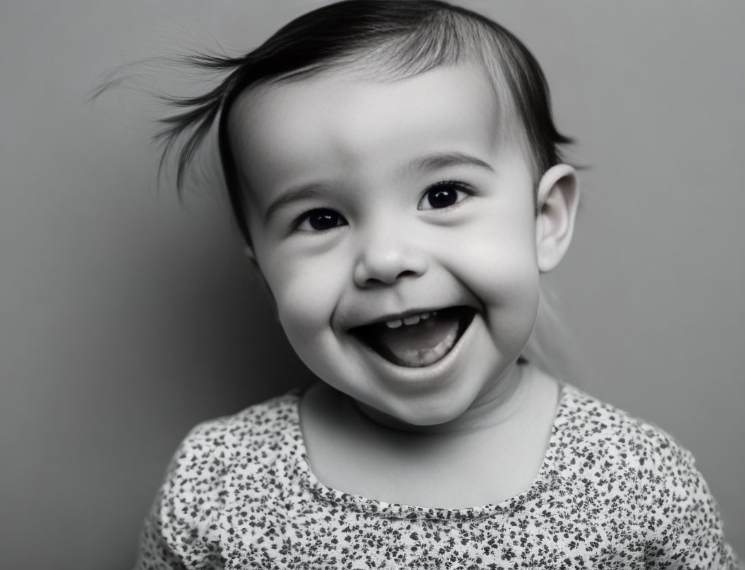 Smiling baby with wispy hair in patterned outfit