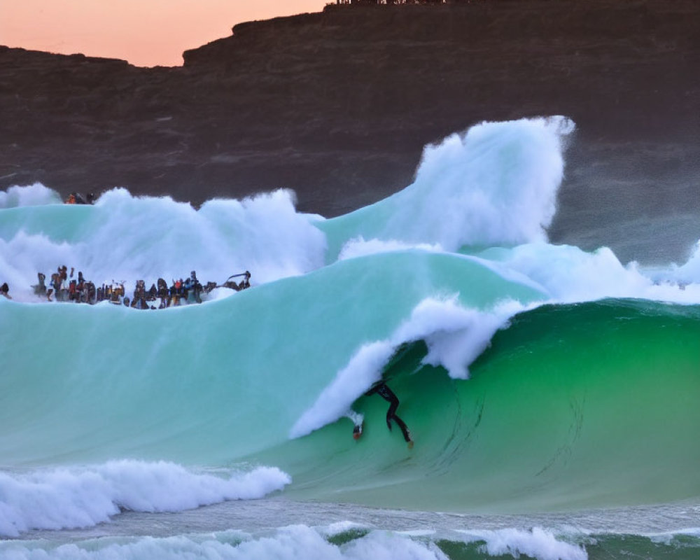 Surfer Riding Large Wave at Sunset with Onlookers on Rocky Cliff