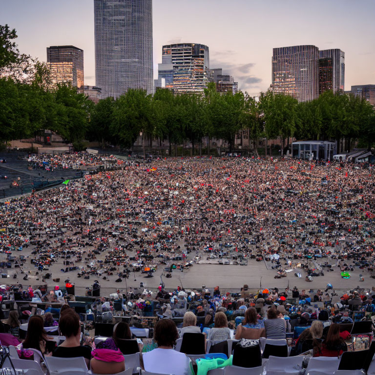 Outdoor Gathering with People Seated Facing Stage at Dusk