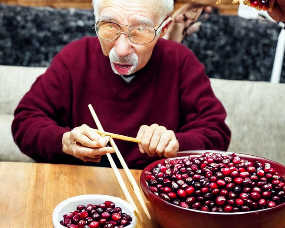 Elderly man eating cherries with chopsticks from large bowl