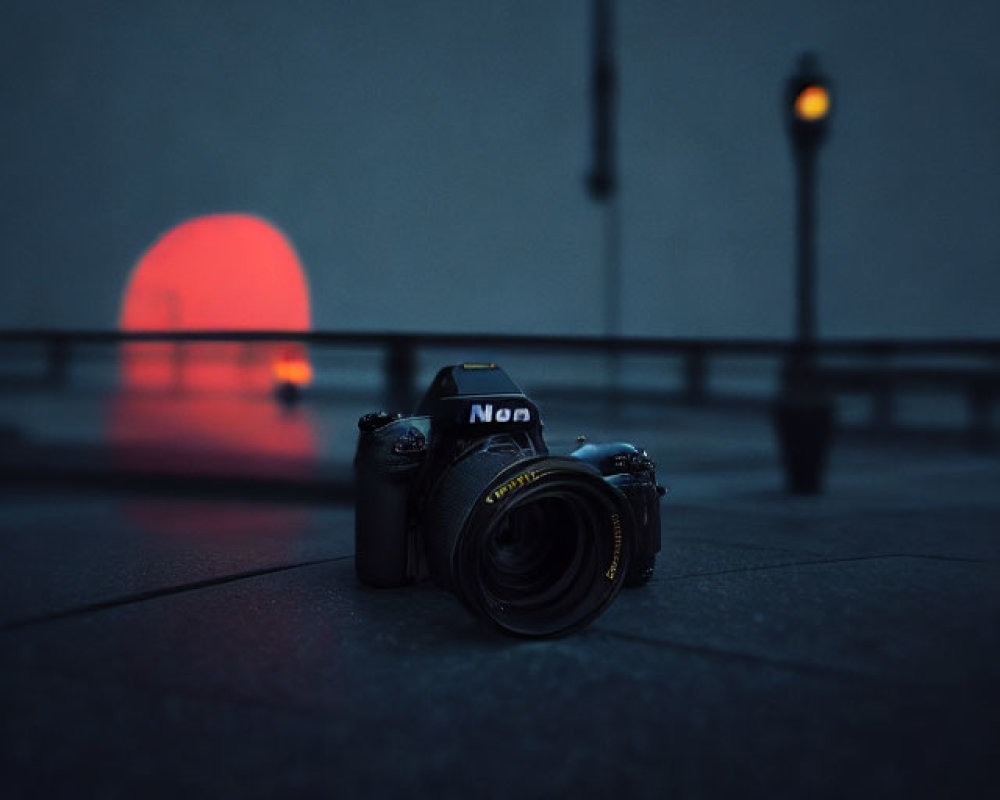 DSLR camera on ground with red circular light and street lamps in background