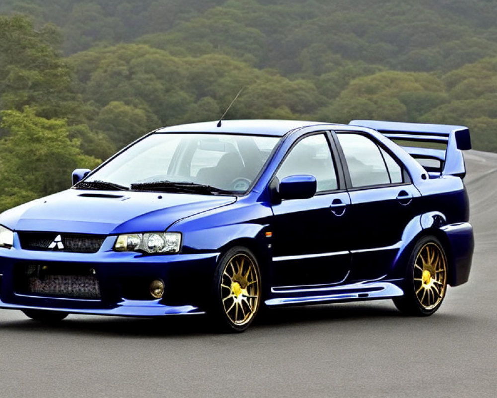 Blue sports sedan with large rear spoiler and yellow rims on road with greenery