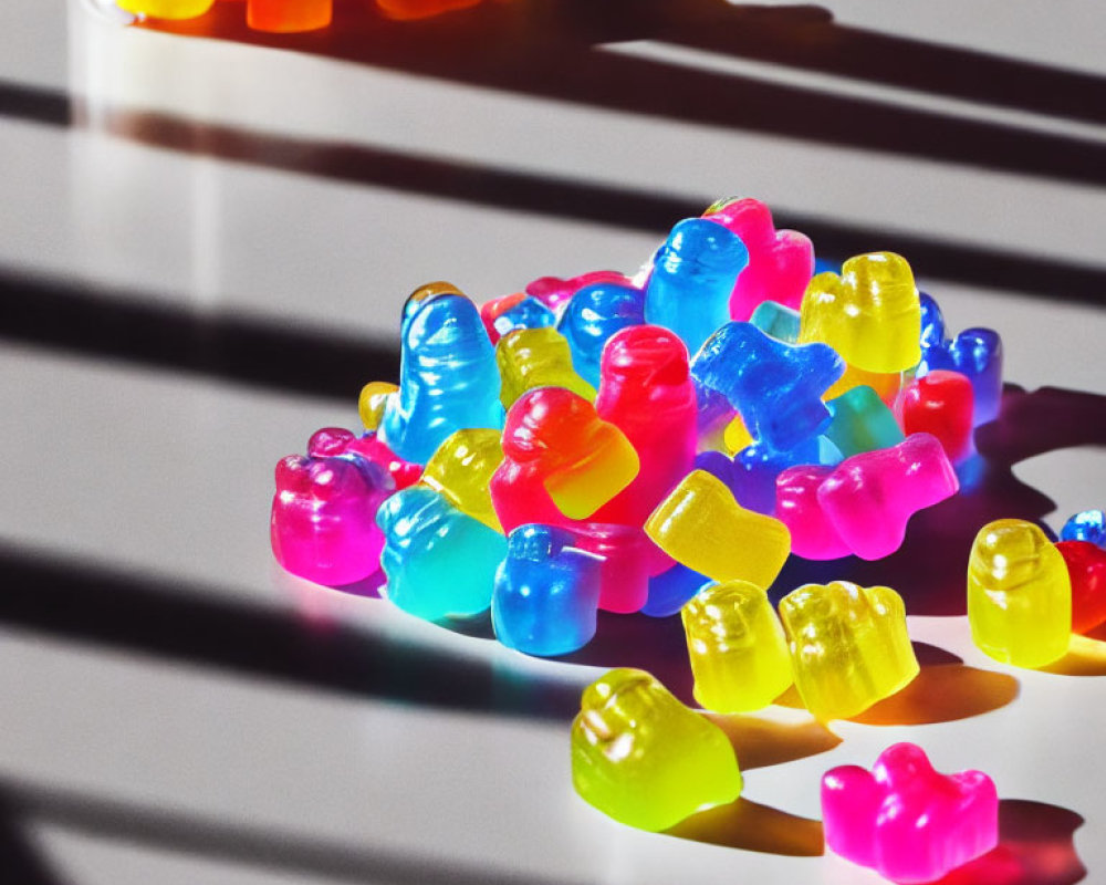 Vibrant gummy bears under sunlight with shadows on white surface