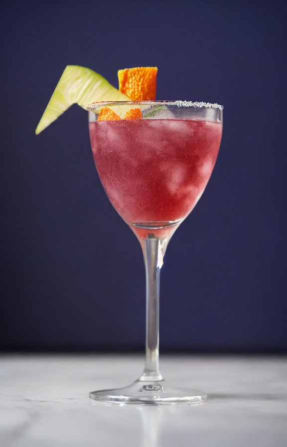 Red Cocktail with Sugar Rim, Lime Wedge, and Orange Peel on Blue Background