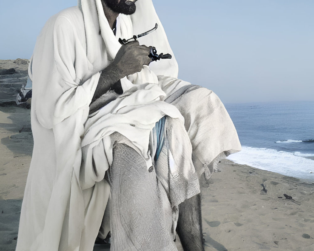 Man in traditional attire smoking pipe on sandy beach