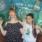 Two women in traditional attire with fantastical cityscape backdrop.