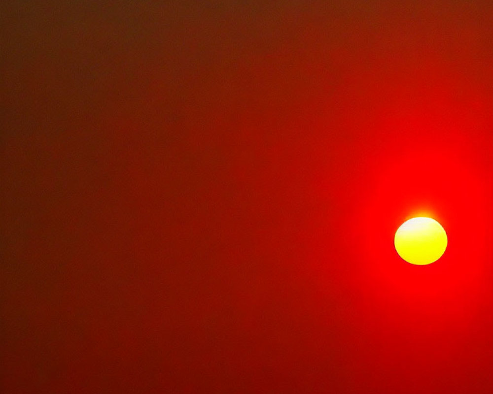 Vivid red sky with partially eclipsed yellow sun on horizon