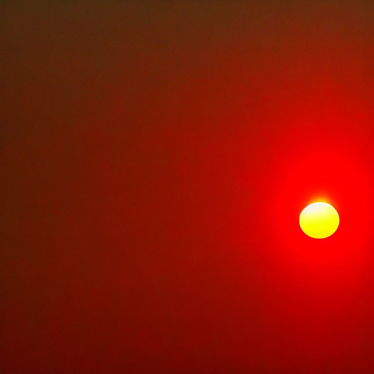 Vivid red sky with partially eclipsed yellow sun on horizon