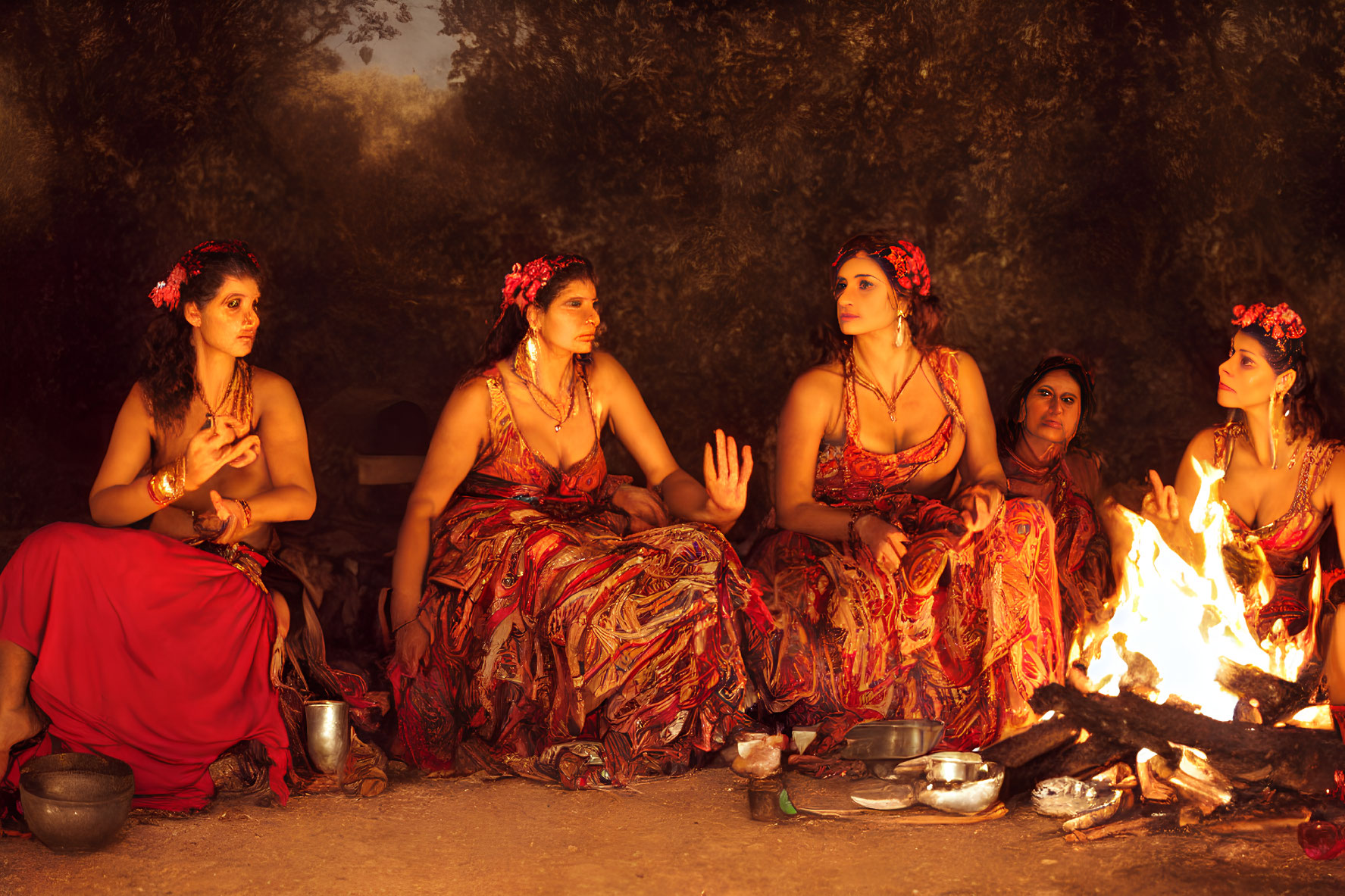 Women in Red Attire Gathered Around Fire in Dusk-lit Wooded Setting