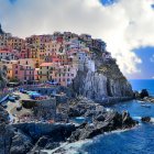 Colorful coastal village with lighthouse, sailboat, and rocky shore