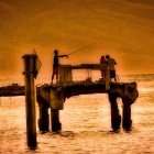 Fishing boats on wavy sea at sunset with vivid orange sky