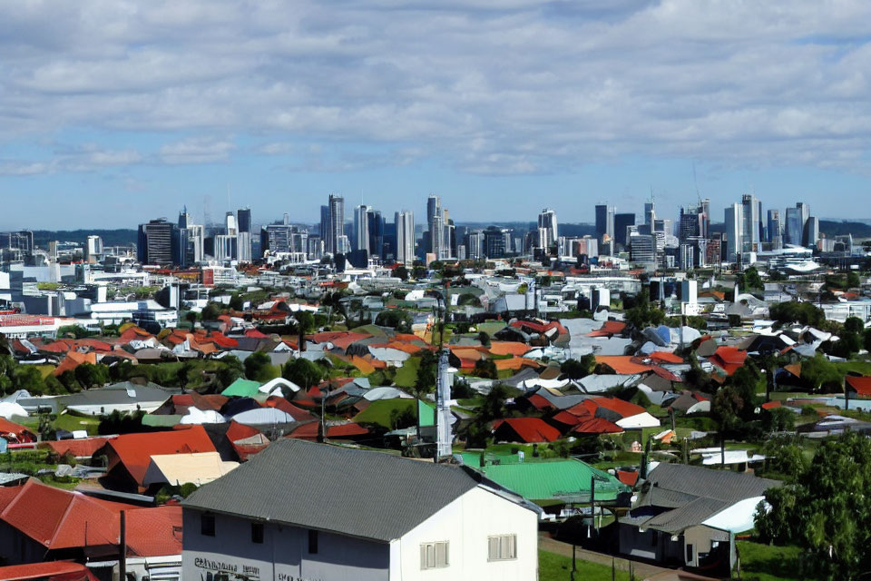 Panoramic view of cityscape with houses and skyscrapers under cloudy sky