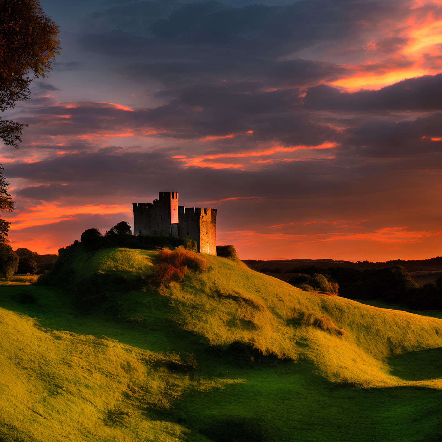 Majestic castle on green hill under dramatic sunset sky