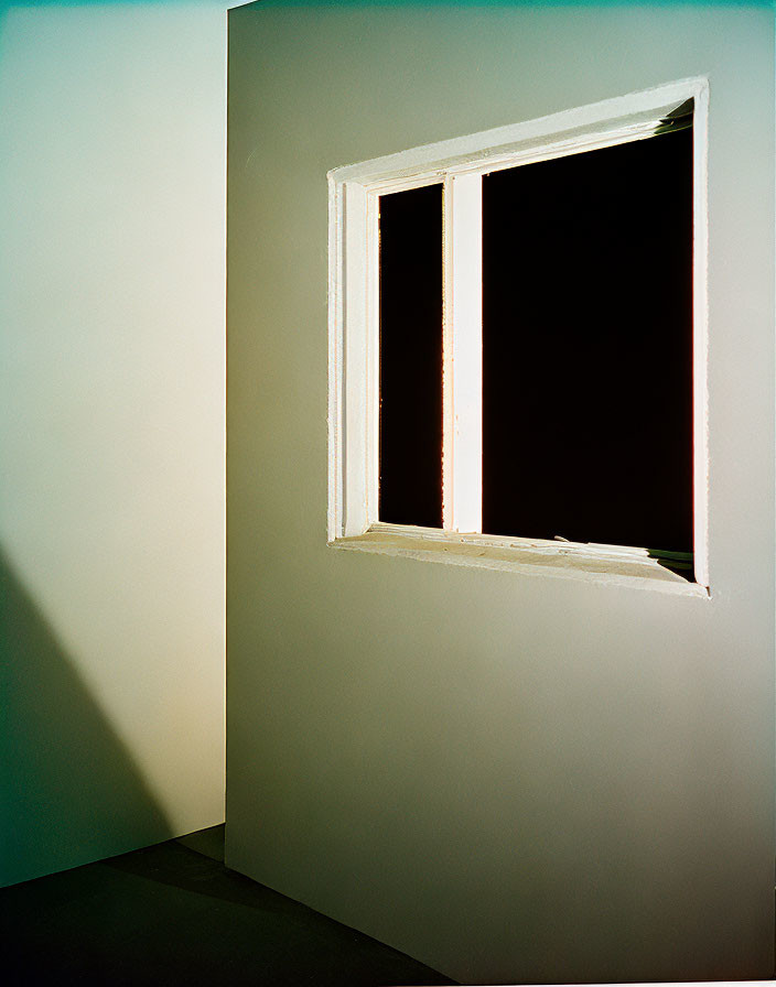 White-framed open window casting shadow on corner wall.