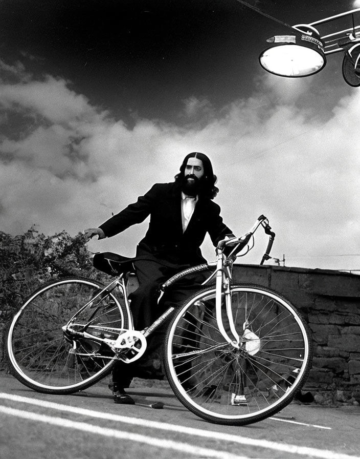 Monochrome photo of bearded man on bicycle with cloudy sky and street lamp