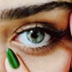 Detailed close-up painting of human eye with iris and lashes, featuring leaf-shaped object.