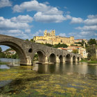 Stone bridge over water in whimsical landscape village under blue sky