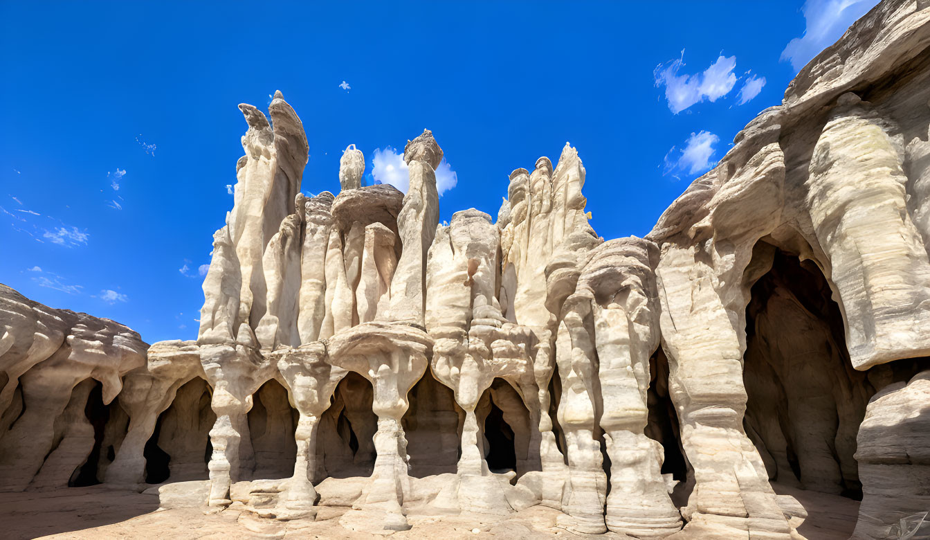 Sandstone Hoodoos with Cave-like Openings Under Blue Sky