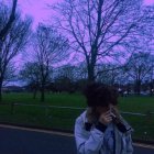 Patterned person on road with trees and dusk sky in background