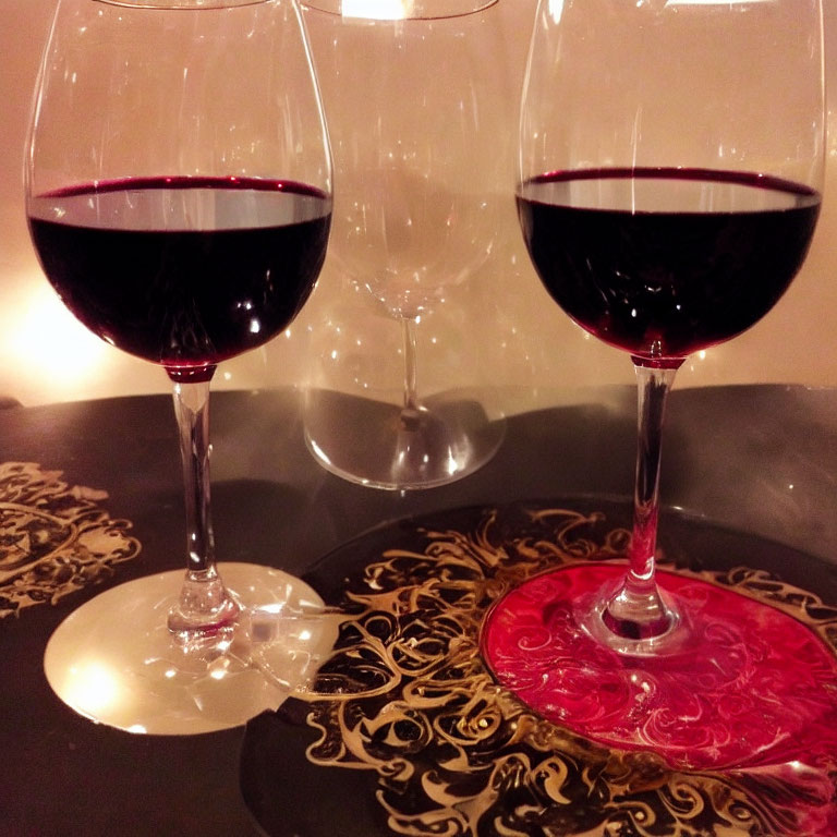 Elegant red wine glasses on table with ornate coasters