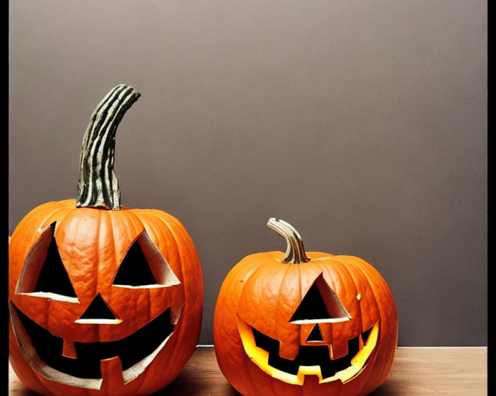 Carved Jack-o'-lanterns with Lit Interiors on Wooden Surface