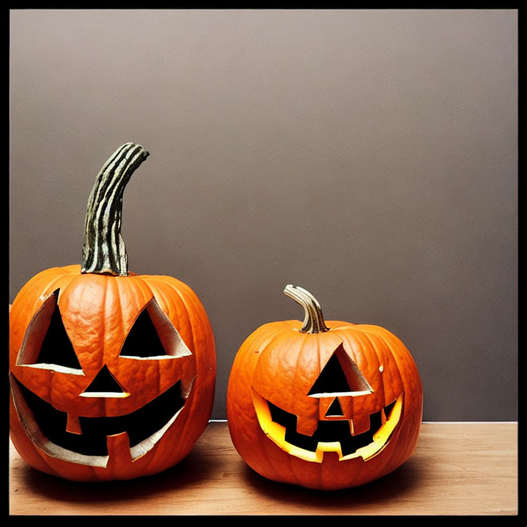 Carved Jack-o'-lanterns with Lit Interiors on Wooden Surface