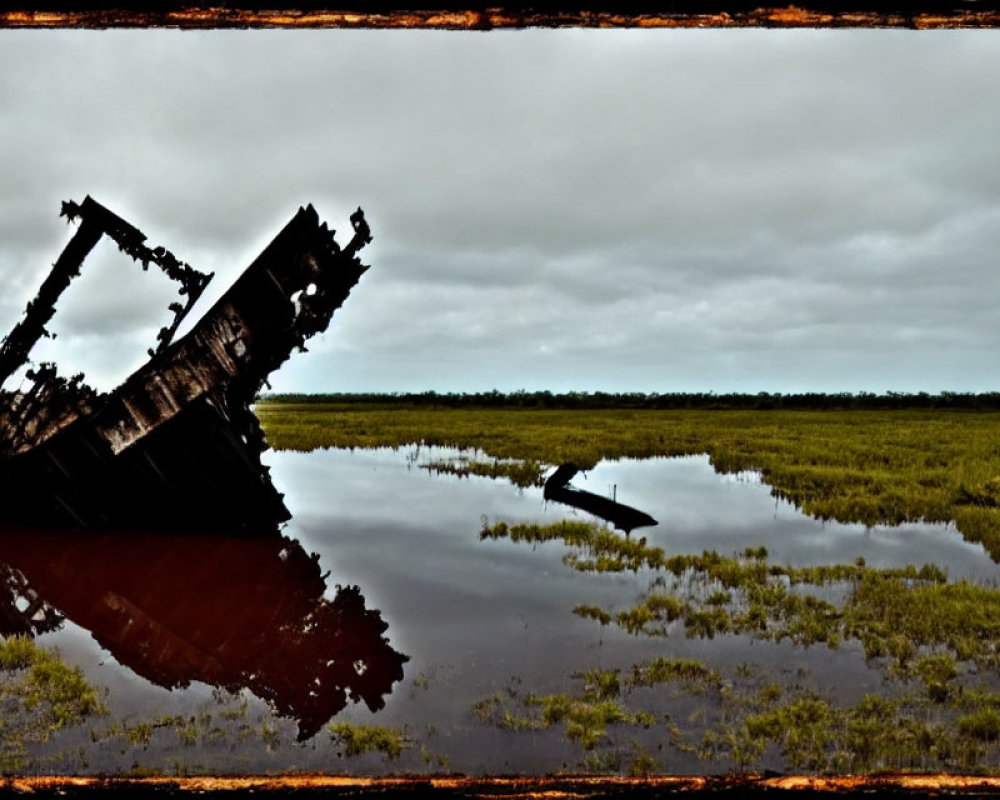 Rusted shipwreck in calm water with cloudy sky