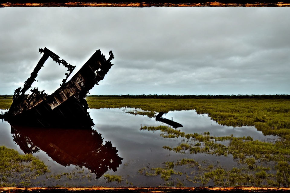 Rusted shipwreck in calm water with cloudy sky