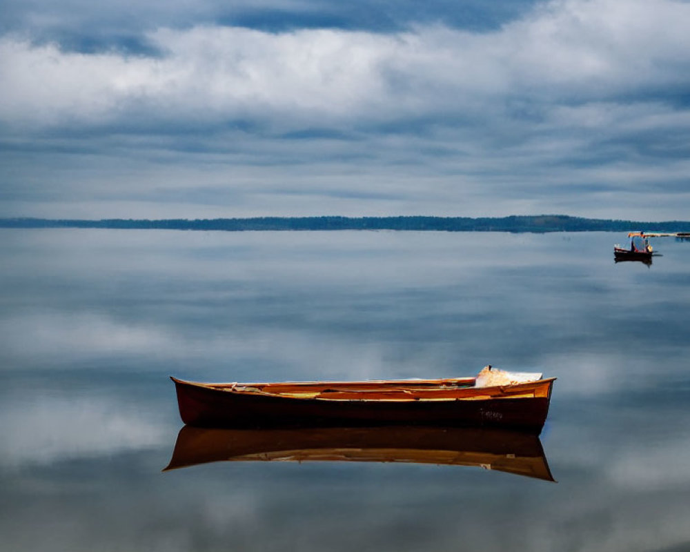 Tranquil scene of wooden canoe on glassy water under cloudy sky